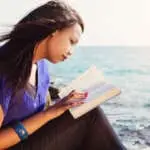 Beautiful Girl reading her Bible by the sea