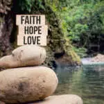Faith hope love text on wooden blocks with blurred nature background.