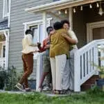 Full length portrait of happy black family embracing on porch of new house, copy space