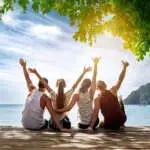 Group of happy friends is sitting and hugging at idyllic sea beach. Phi-phi island, Krabi, Thailand
