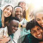 Happy multiracial friends having fun hanging out on city street - Group of young people laughing out loud together outside - Friendship concept with guys and girls enjoying weekend