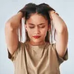 Headache, annoyed and anxiety of woman in studio with pressure and frustrated. Mental health issue, young female and migraine of worker with a head massage and stress problem with blurred background