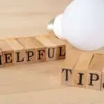 HELPFUL TIPS; Wooden stamps with "HELPFUL TIPS" text of concept and a light bulb on the table.