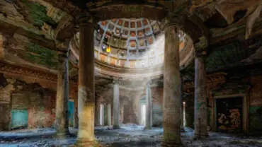 Interior of old ruined palace with columns and dome.