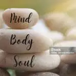 Light shining on zen stones with words Mind, Body, Soul on blurred background. Customize space for text or ideas.
