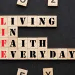 Living in faith everyday in wooden blocks on black background. Acronym Life