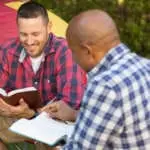 Men having a bible study on a camping trip.