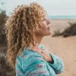 One woman enjoy inner balance and meditation leisure outdoor activity alone feeling nature hugging herself at the beach. Side portrait of zen lifestyle and happiness female people. Closed eyes love
