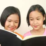 Portrait of two girls reading book.