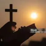 Silhouette of Young woman hands holding holy Bible and lift of christian cross, religion symbol in light and landscape over a sunrise, background, religious, faith concept