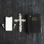 Study Bible worship online concept. Church online Sunday new normal concept. Bible, cell phone and earbuds on a wood background. Home church