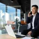 Thinking asian businessman businessman, talking on the phone working in a modern office, listening seriously