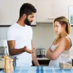 Young russian interracial family couple with serious faces quarrelling in kitchen. focus on