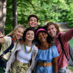 Portrait of group of young friends on camping trip near lake in summer.