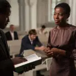 Waist up portrait of mature African American woman talking to priest during Sunday service in church