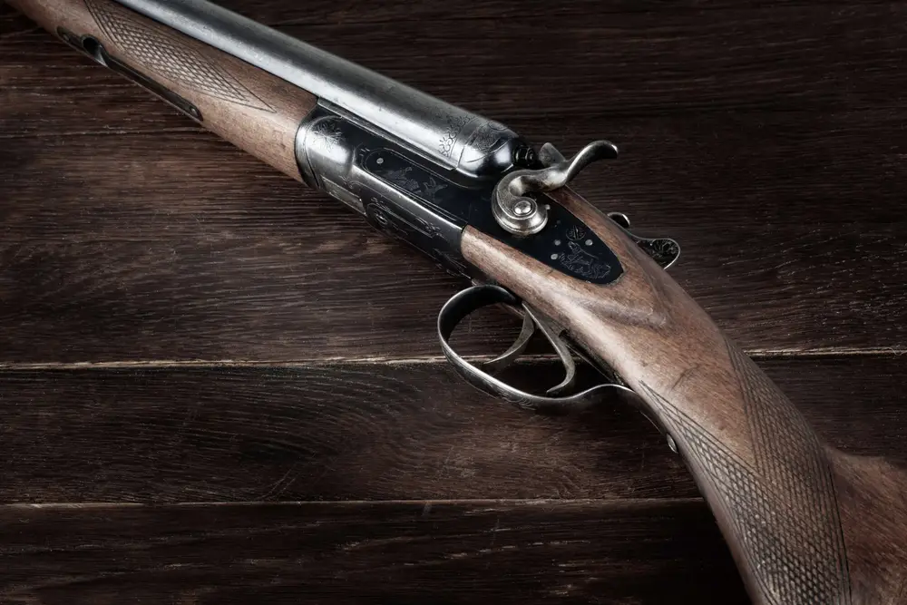 double barreled side shotgun on wooden table.